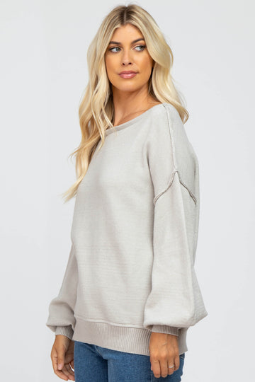 woman wearing a light gray oversized sweater with balloon sleeves and a relaxed fit
