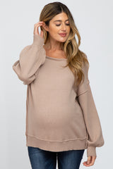 woman wearing a beige maternity sweater with a relaxed fit and balloon sleeves, showing her baby bump
