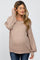woman wearing a beige maternity sweater with a relaxed fit and balloon sleeves, showing her baby bump