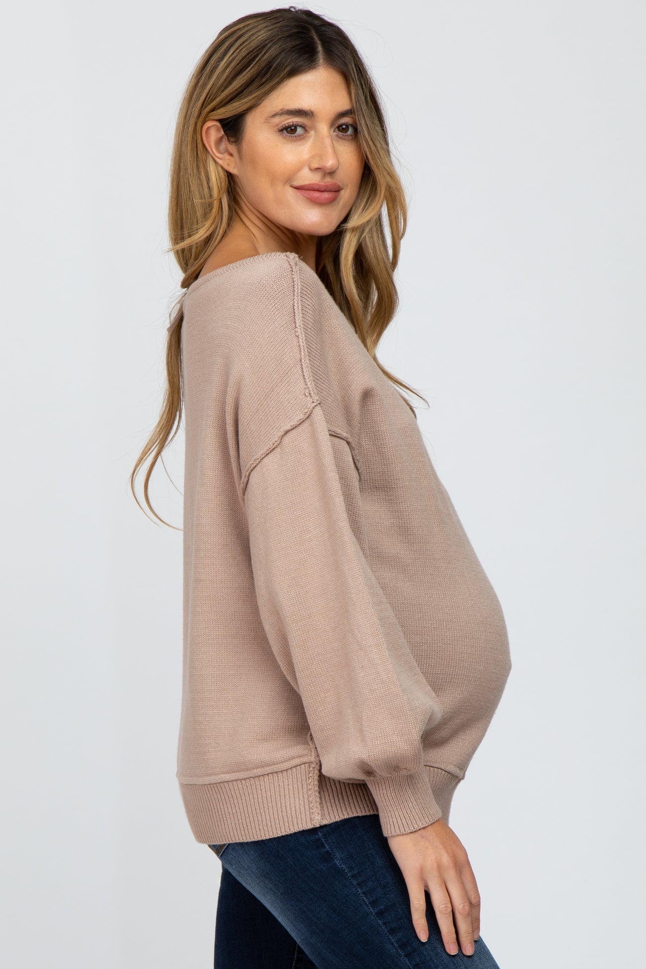 woman wearing a light beige oversized maternity sweater with balloon sleeves and a visible baby bump