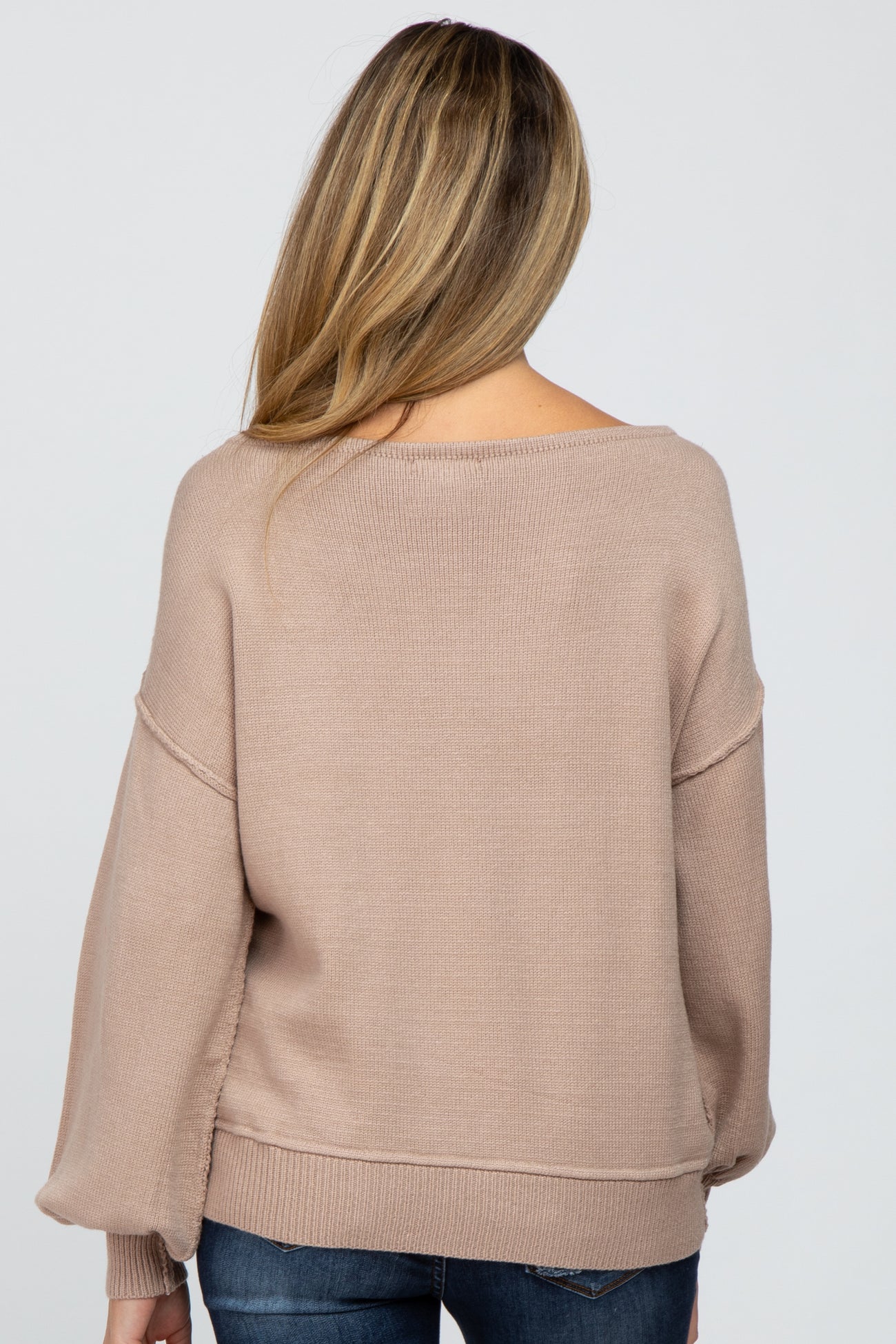 woman wearing a light brown oversized knit maternity sweater from the back, with cozy long sleeves and a relaxed fit