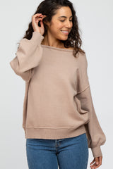 woman wearing a beige oversized sweater with a relaxed fit and wide neckline, paired with blue jeans
