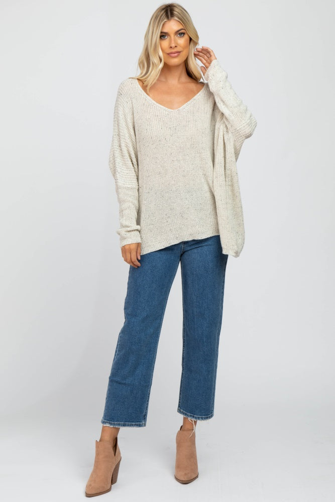 woman wearing a cream oversized knit sweater and blue wide-leg jeans with taupe ankle boots