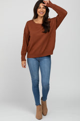 woman wearing a brown oversized sweater with cable knit sleeves paired with skinny jeans and ankle boots