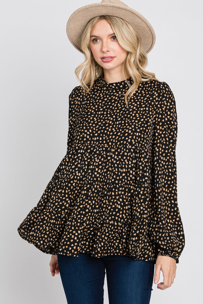 woman wearing a black and tan polka dot peplum blouse with long sleeves and a high neckline, styled with a hat