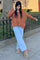 woman wearing a rust orange oversized cable knit sweater and light blue wide-leg jeans with tan ankle boots
