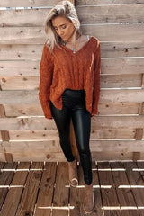 woman wearing an oversized orange cable knit sweater with black leather leggings and tan ankle boots