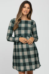 woman wearing a green and gray plaid maternity dress with long sleeves and a fitted waist, showing her baby bump