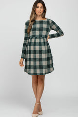 woman wearing a green and cream checkered maternity dress with long sleeves and a baby bump visible