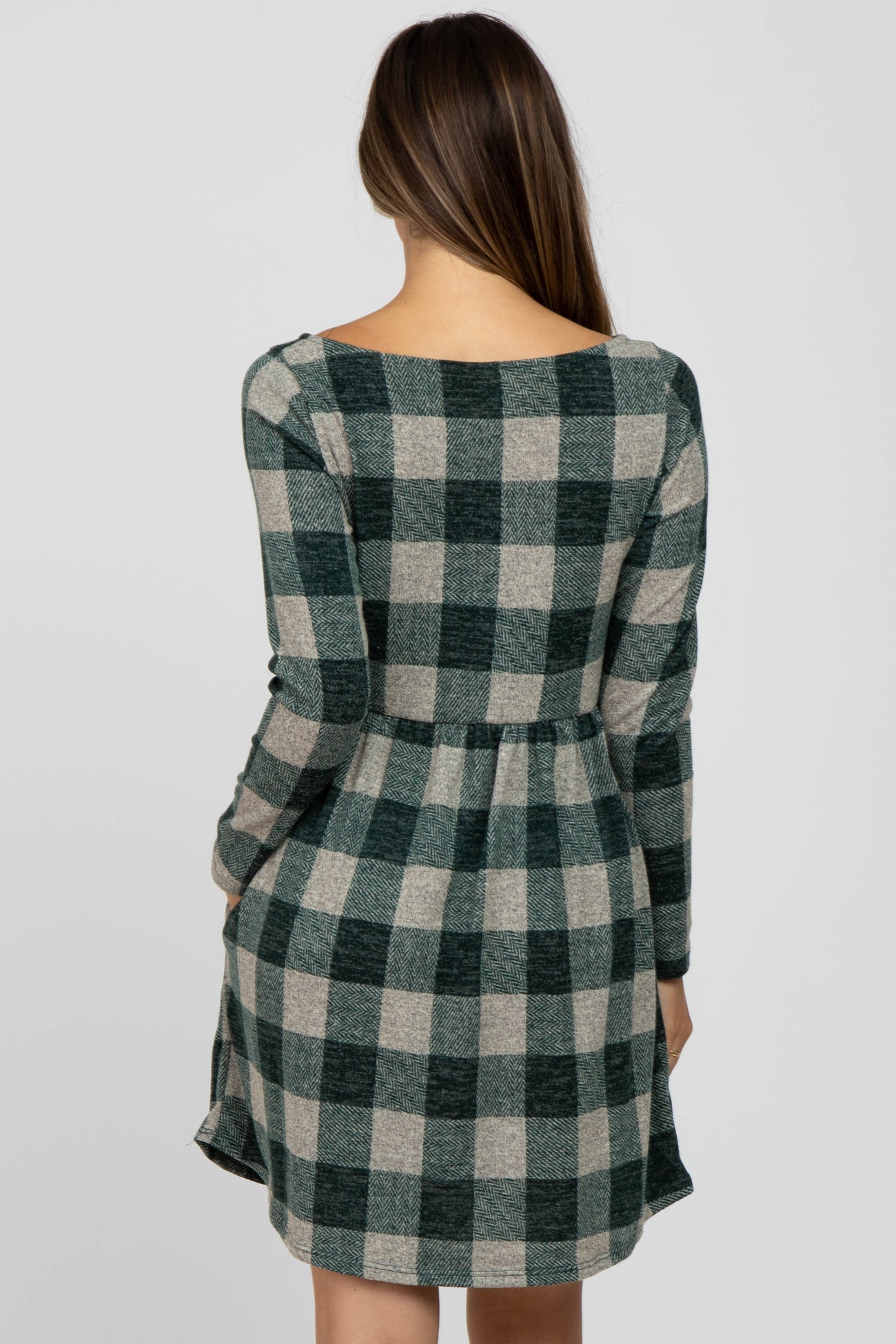 woman wearing a green and beige plaid long sleeve maternity dress from the back