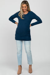 woman wearing a navy blue long sleeve maternity top with ruched sides and light blue jeans, showing her baby bump