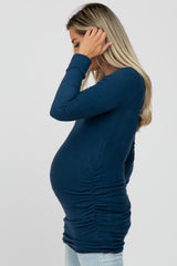 woman wearing a dark blue long sleeve maternity top, showing her baby bump with gathered side details