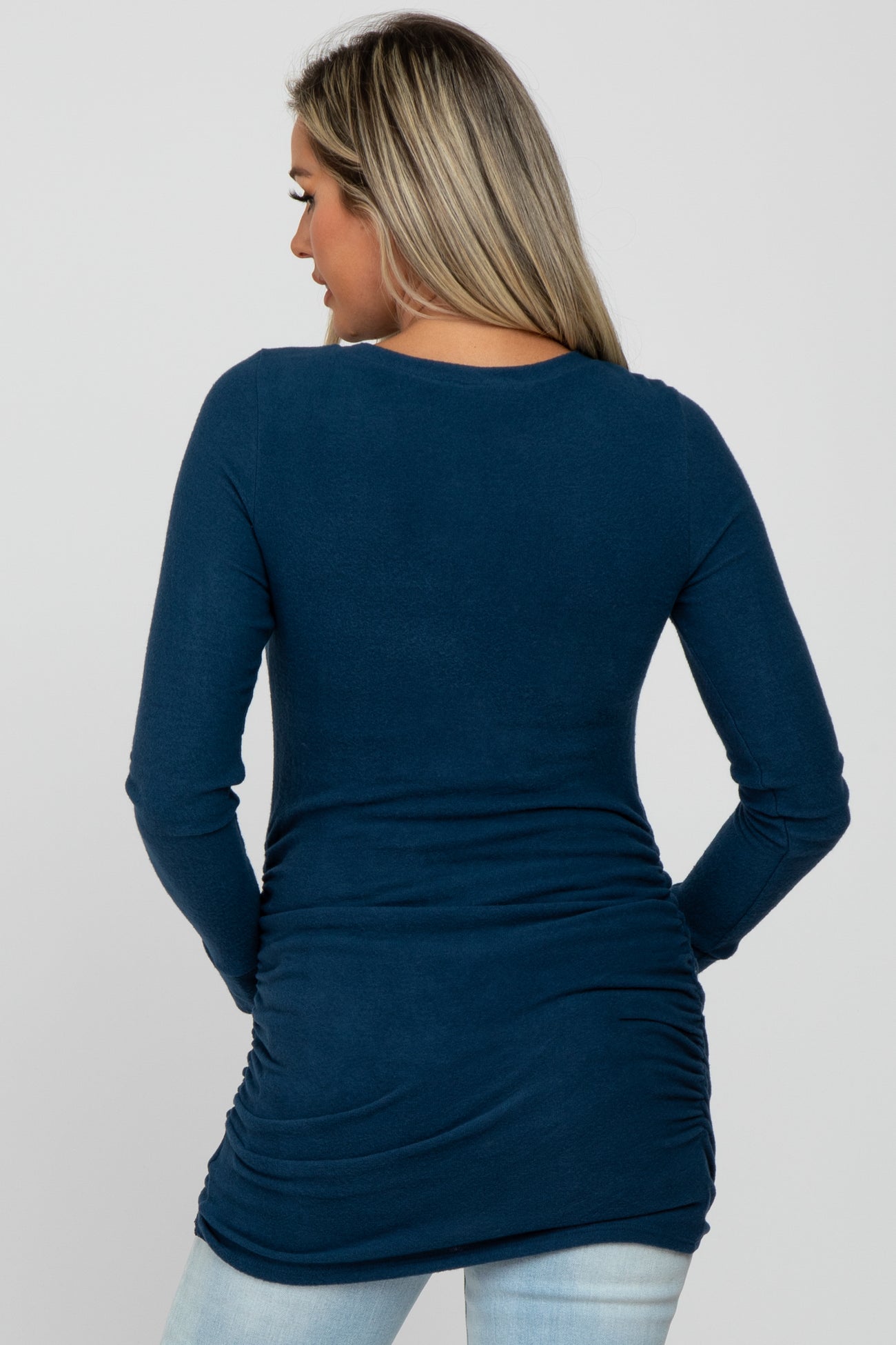 woman wearing a navy blue long sleeve maternity top with ruching detail at the sides, showing her back