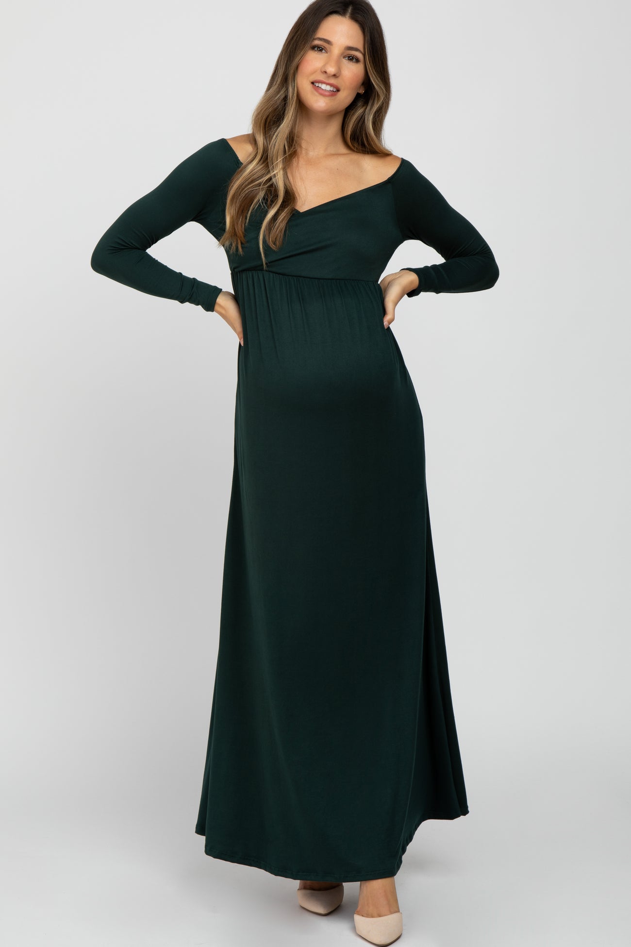 woman wearing a dark green off-shoulder maternity dress with long sleeves and a visible baby bump