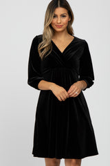 woman wearing a black velvet wrap dress with three-quarter sleeves and a gathered waist