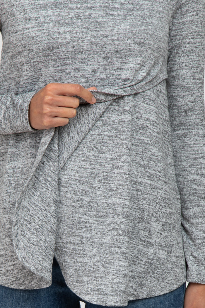 woman wearing a gray long sleeve top with a draped front detail, paired with blue jeans