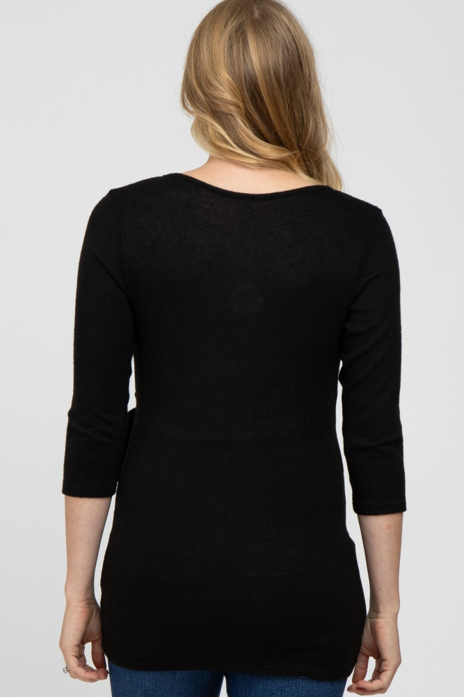 woman wearing a black maternity top with three-quarter sleeves, viewed from the back