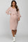 woman wearing a light pink maternity dress with long sleeves and a waist tie, showcasing her baby bump