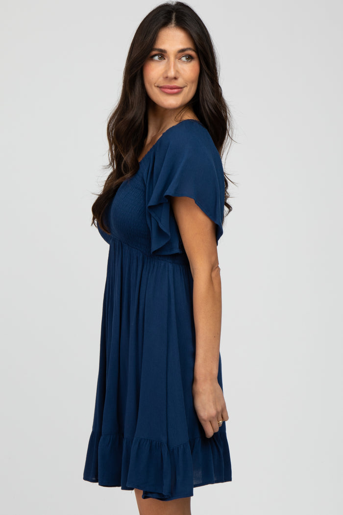 woman wearing a navy blue short sleeve dress with ruffle details and a fitted bodice