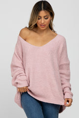 woman wearing a light pink oversized off-the-shoulder sweater with a textured knit design and relaxed fit
