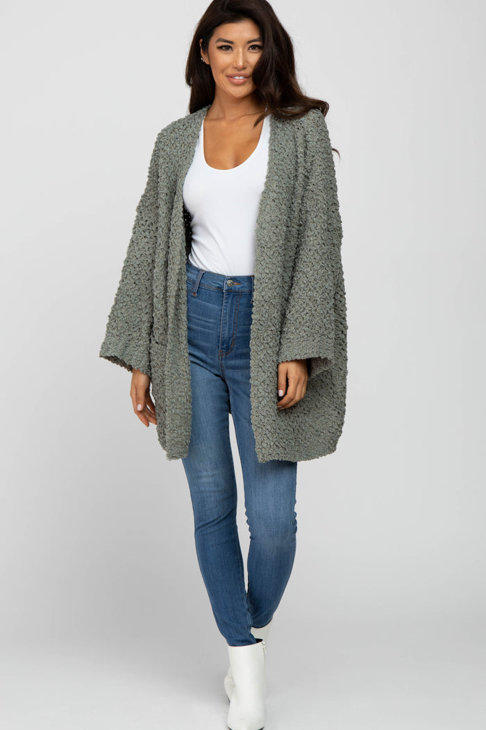 woman wearing a light gray textured open cardigan over a white top and high-waisted skinny jeans