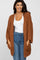 woman wearing an oversized rust-colored fuzzy cardigan over a white top and blue jeans