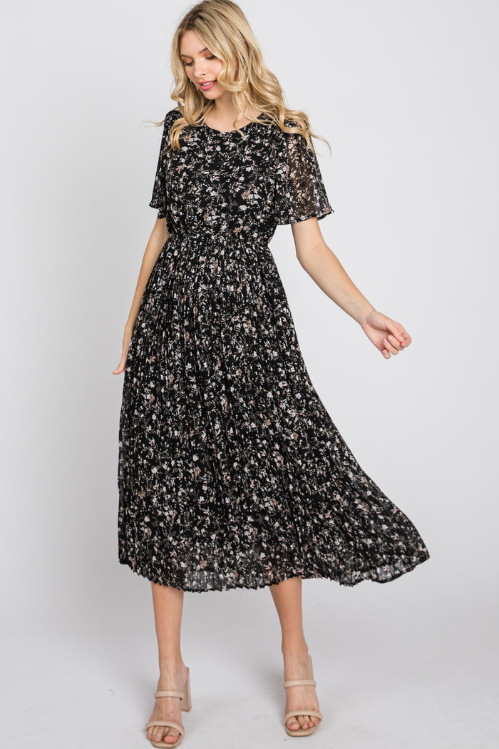 woman wearing a black floral midi dress with short sleeves and a smocked bodice, styled with strappy heels