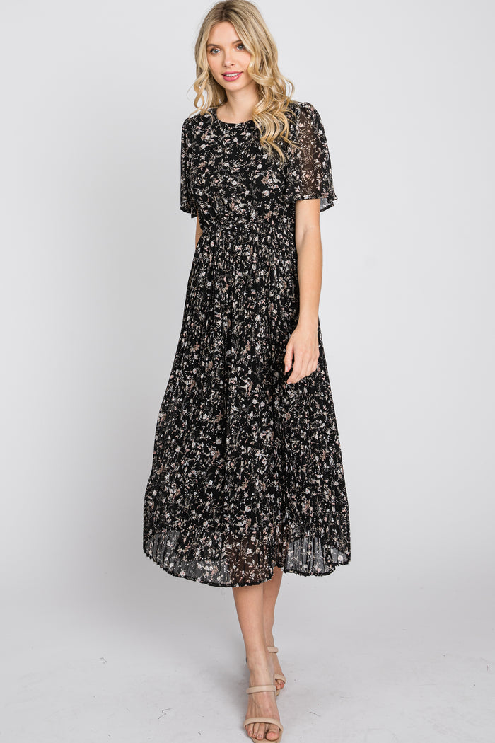 woman wearing a black floral midi dress with short sleeves and a pleated skirt