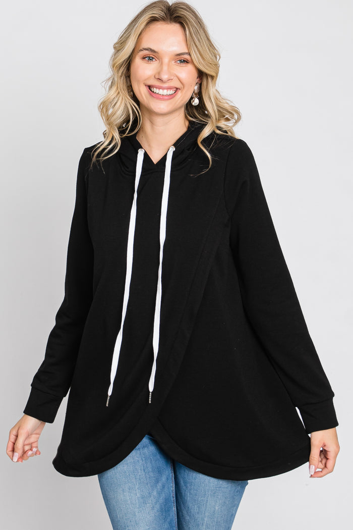 woman wearing a black oversized hoodie with white drawstrings and a flowy hem, paired with blue jeans
