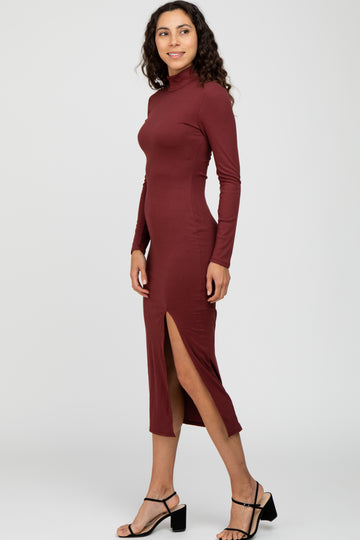 woman wearing a maroon long sleeve ribbed midi dress with a side slit and styled with black strappy heels