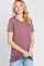 woman wearing a mauve short sleeve t-shirt with a relaxed fit and side ruching, smiling at the camera