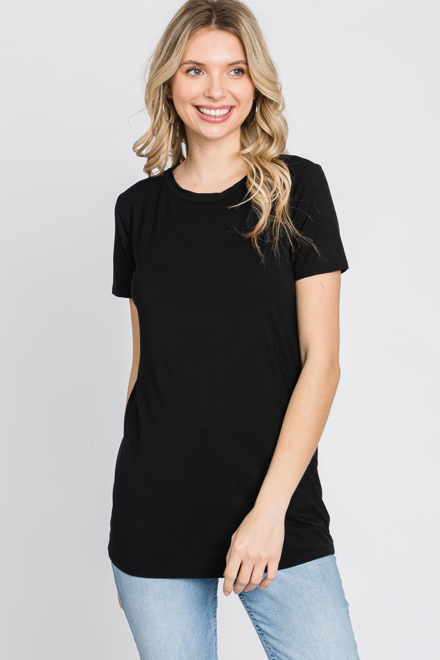 woman wearing a black short sleeve t-shirt and light blue jeans, smiling at the camera
