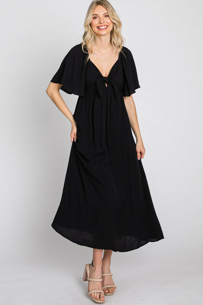 woman wearing a black maxi dress with flutter sleeves and a tie front detail