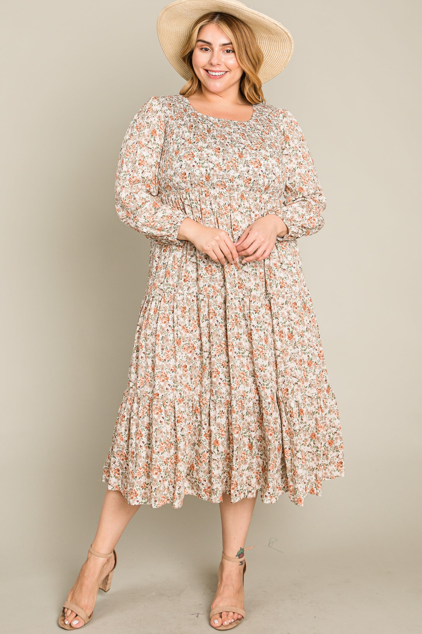 woman wearing a floral print midi dress with long sleeves and a tiered skirt, paired with a wide-brimmed hat and sandals
