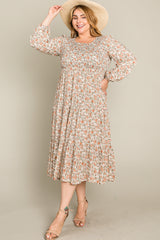 woman wearing a floral print mid-length dress with long sleeves and a fitted bodice, accessorized with a wide-brim hat