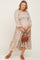 woman wearing a floral long sleeve maternity dress and holding her baby bump with a small brown handbag
