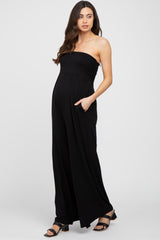 woman wearing a black strapless maternity jumpsuit with side pockets and a visible baby bump