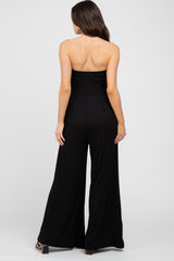 woman wearing a black strapless maternity jumpsuit, back view, with wide legs and a fitted bodice
