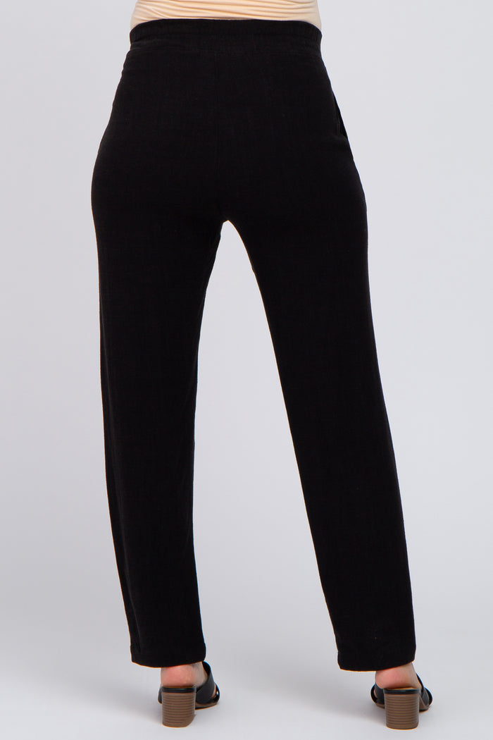 woman wearing black maternity pants, shown from the back, featuring a relaxed fit and subtle texture