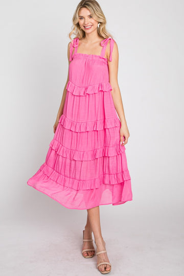 woman wearing a hot pink tiered midi dress with tie straps and ruffle details