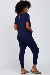 woman wearing a navy blue short sleeve jumpsuit with a back keyhole detail and side pockets