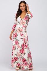 woman wearing a floral maxi maternity dress with a wrap design and three-quarter sleeves, showcasing a baby bump