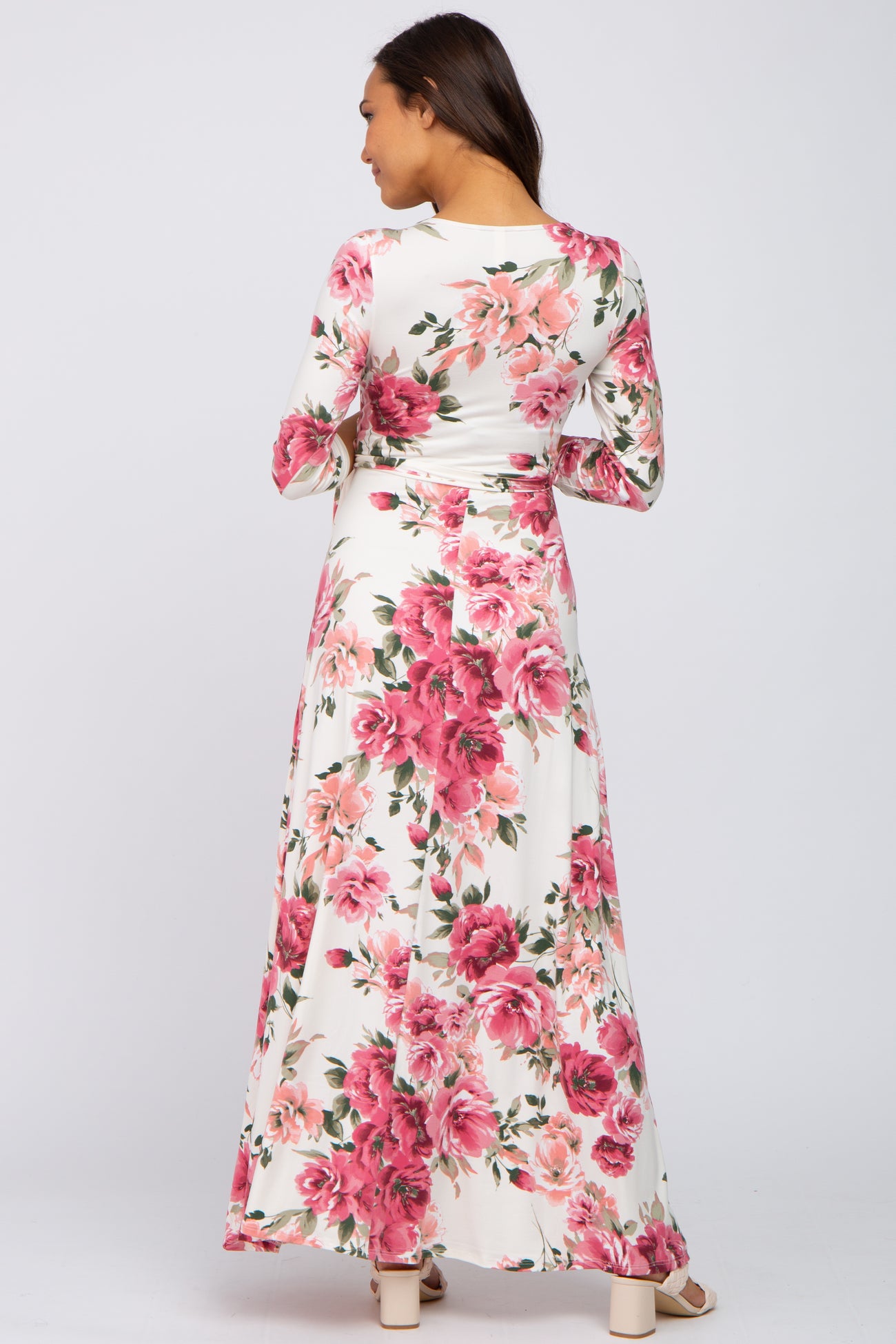 Woman wearing a long sleeve white floral maxi dress with pink and red flowers, viewed from the back