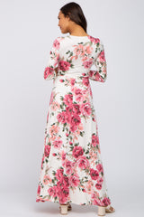 Woman wearing a long sleeve white floral maxi dress with pink and red flowers, viewed from the back