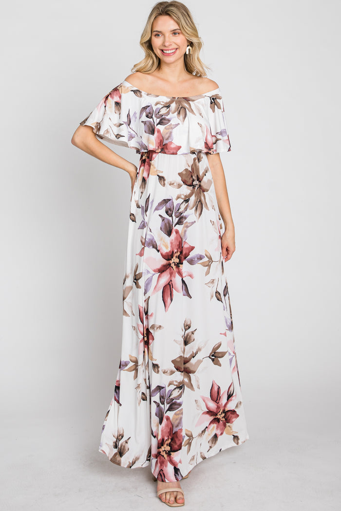 woman wearing a white off-the-shoulder maxi dress with a large floral print in shades of pink and purple