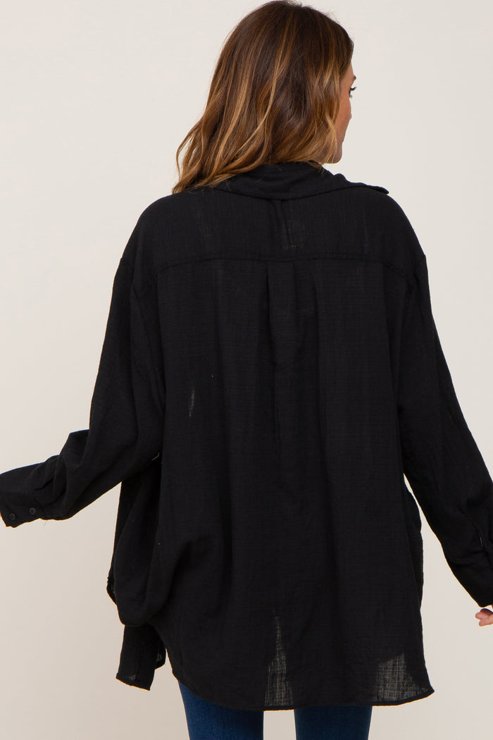 woman wearing a loose black button-up shirt, seen from the back, with long sleeves and a relaxed fit