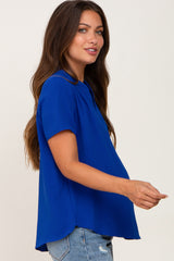woman wearing a bright blue short sleeve maternity top and showcasing her baby bump