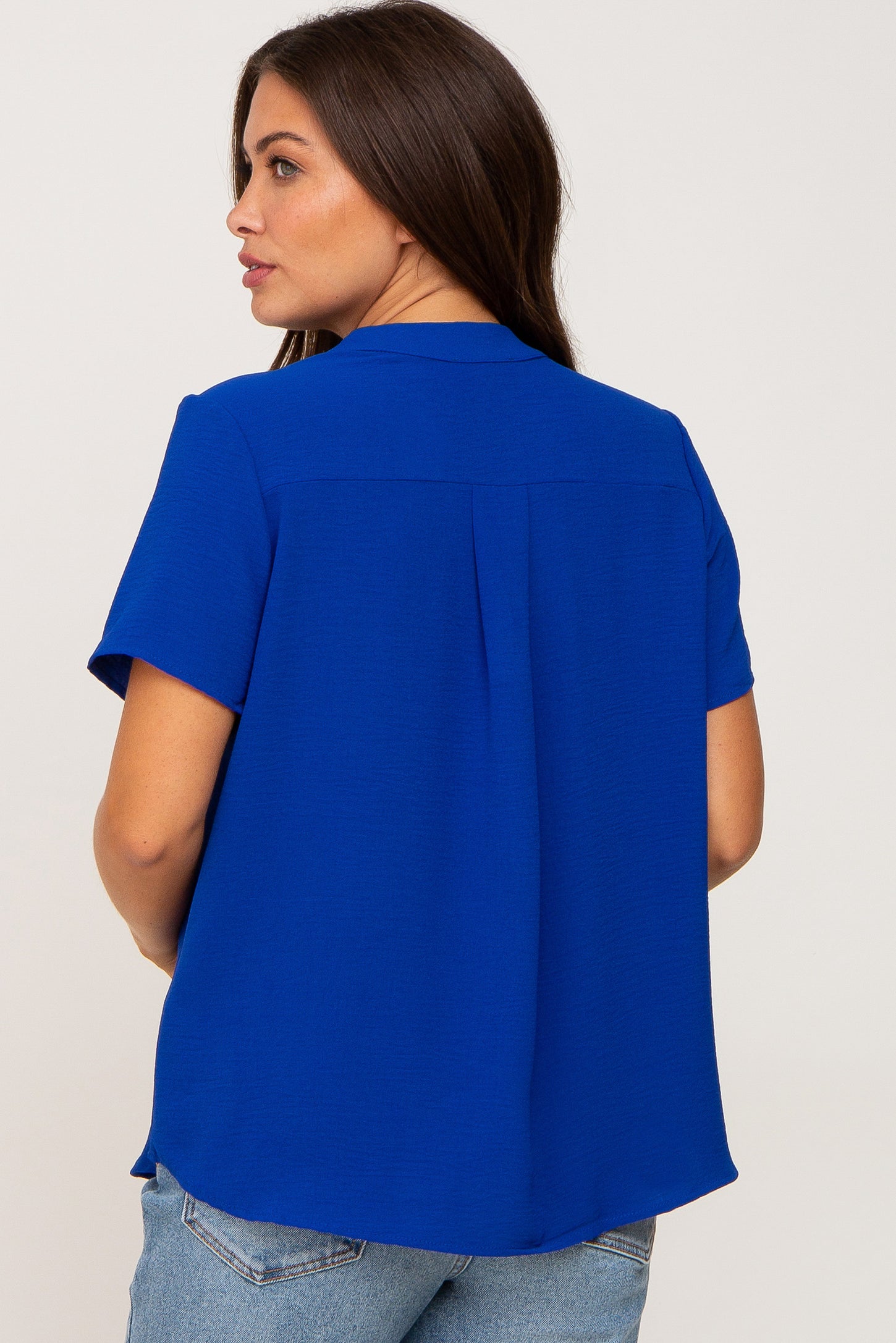 woman wearing a royal blue short sleeve maternity top, viewed from the back