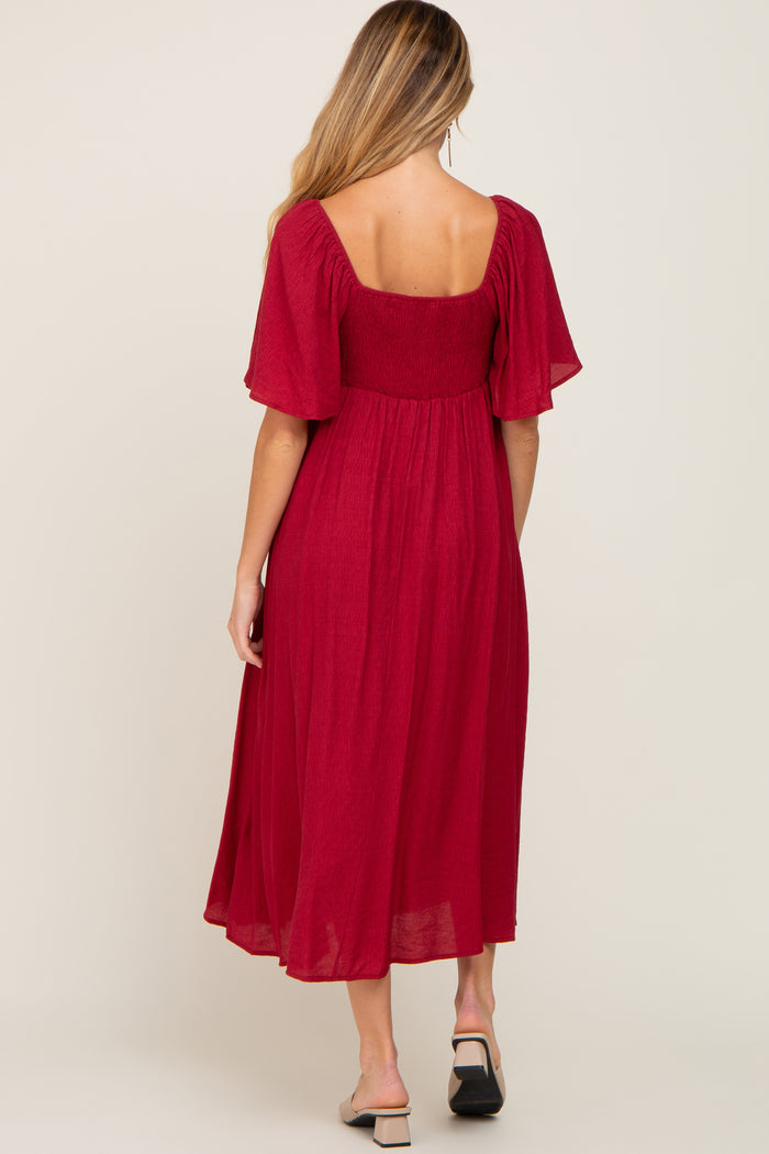 woman wearing a red maternity dress with short flutter sleeves and a flowy skirt, showing the back view