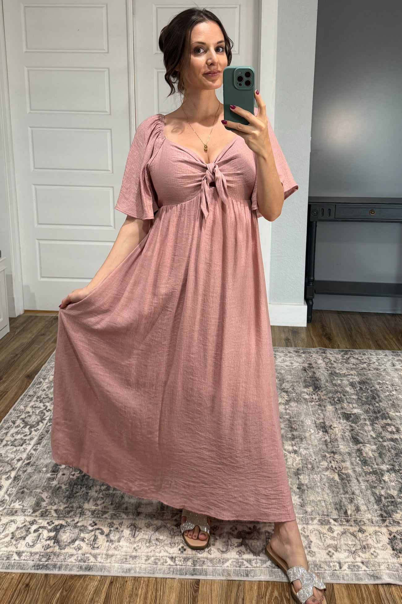 woman wearing a dusty rose maternity maxi dress with a knotted front and short flutter sleeves, showcasing her baby bump